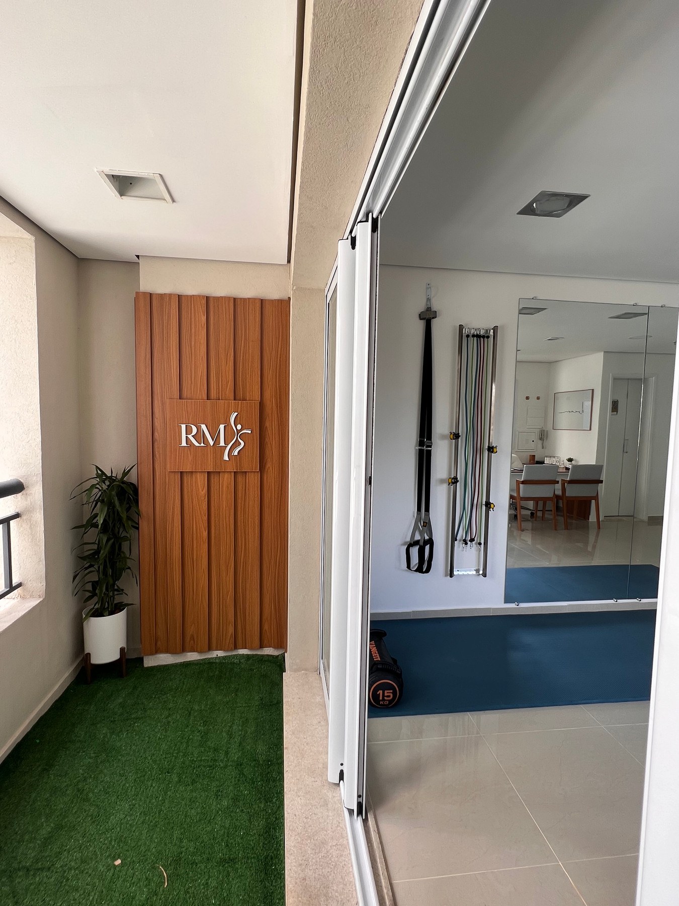 Entrada da clínica com painel de madeira e logo RM